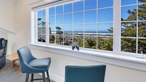 A room with a large window offering a view of the ocean and a cityscape. There are two blue chairs and a small wooden table. - PUMA POINT...Overlooks the Alsea Bay...Has perfect ocean sunset views! Sleeps 3. (Waldport)
