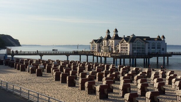 A beachside building with a pier extending into the water, surrounded by rows of beach chairs. - 3 bedrooms to 6 people, Sauna, terrace, 4 * equipment, sea view (Sellin)