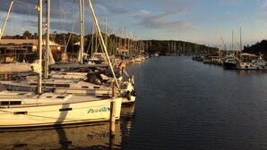 A marina with multiple sailboats docked along a calm waterway, surrounded by buildings and trees. - 3 bedrooms to 6 people, Sauna, terrace, 4 * equipment, sea view (Sellin)