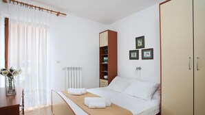 Ein ordentlich eingerichtetes Schlafzimmer mit einem Bett, einem Kleiderschrank, einem Heizkörper und gerahmten Bildern an der Wand.
