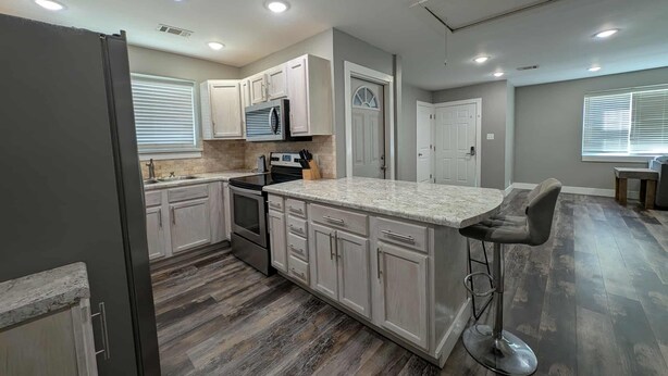 A modern kitchen with white cabinets, a granite countertop, and a stainless steel range hood. - Main Street Lodge 2 mins to Downtown Jonesboro and St. Bernards (Jonesboro)