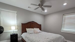 A bedroom with a bed, a ceiling fan, a nightstand, and a window with blinds. - Main Street Lodge 2 mins to Downtown Jonesboro and St. Bernards (Jonesboro)