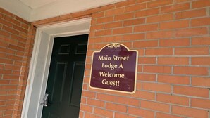 A brick wall with a door and a sign that reads 'Main Street Lodge A Welcome Guest!' - Main Street Lodge 2 mins to Downtown Jonesboro and St. Bernards (Jonesboro)