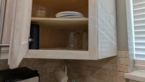 A wooden cabinet with shelves containing plates, glasses, and a pitcher. - Main Street Lodge 2 mins to Downtown Jonesboro and St. Bernards (Jonesboro)