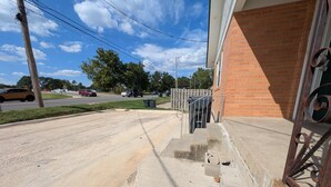 A residential street with a brick house, a metal gate, and a concrete sidewalk. - Main Street Lodge 2 mins to Downtown Jonesboro and St. Bernards (Jonesboro)