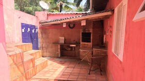 A small, enclosed outdoor area with a brick oven, a chair, and a table. - House 2 suites + 2 apartments - 12 people, Foot of the hill, nature at your window (Praia de Barequecaba)