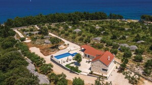 A coastal property with a swimming pool, stone house, and surrounding greenery. - Luxurious home in Supetar (Supetar)