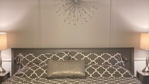 A bed with patterned bedding, a fluffy white throw, and a decorative wall piece above it. - King Size Master With Attached Bath,Pool Table, Open Kitchen,2 Full Baths (Bethel)