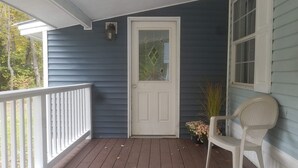A porch with a white door, a white chair, and a potted plant. - King Size Master With Attached Bath,Pool Table, Open Kitchen,2 Full Baths (Bethel)