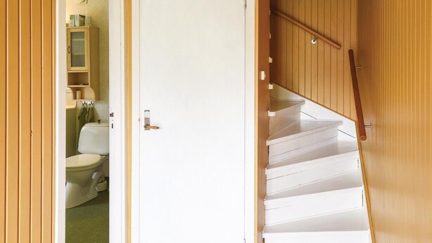 A staircase with wooden steps and a handrail, leading to a room with a toilet and cabinets. - 3 bEdroom cozy home in Ed (Ed)