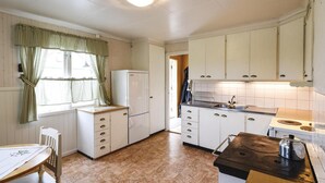 A compact kitchen with white cabinets, a refrigerator, a sink, and a stove. - 3 bEdroom cozy home in Ed (Ed)