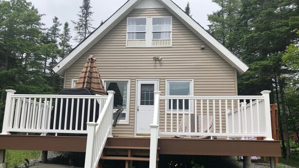 A two-story house with a front porch, a covered staircase, and a small deck.