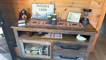 A rustic wooden cabinet with a sign reading 'PARSON'S CABIN,' a bear figurine, a candle, a picture frame, and a lantern.