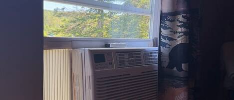 Ein Zimmer mit Fenster, Klimaanlage und Vorhang.