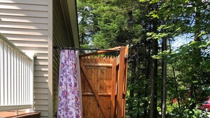 A wooden gate leading to a gravel path with a wooden deck and a house in the background.