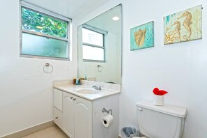 Ein Badezimmer mit Waschbecken, Spiegel, Toilette und zwei gerahmten Kunstwerken an der Wand.
