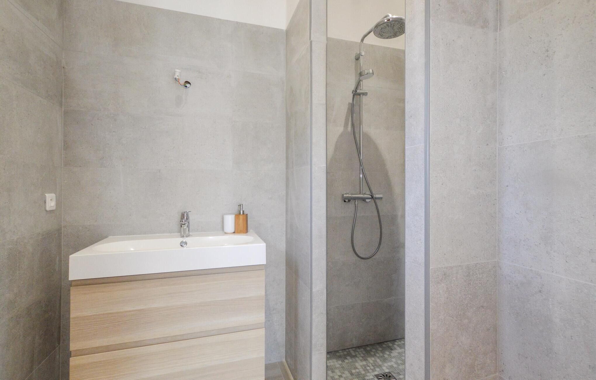 Ein modernes Badezimmer mit Dusche, Waschbecken und einem Holz-Waschtisch.