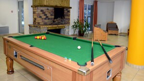 A pool table with balls, a brick fireplace, and a potted plant.