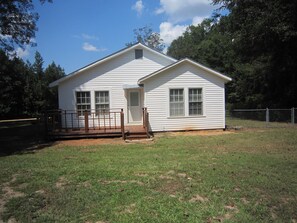 Back of the house with deck that looks out into a fenced backyard