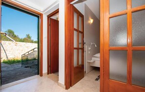 A bathroom with a wooden door, a shower, and a sink.