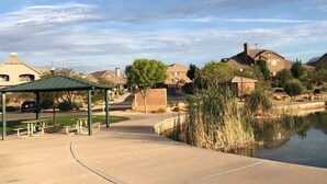 A park with picnic tables, a pond, and houses in the background. - Your home away from home! (Washington)