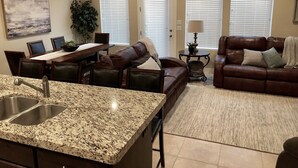 A modern kitchen with granite countertops, a dining area with a table and chairs, a leather sofa, and a ceiling fan. - Your home away from home! (Washington)