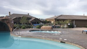 A pool area with a hot tub, lounge chairs, and a building with a stone facade. - Your home away from home! (Washington)