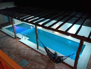 Relax by the pool under a shaded pergola, where a hammock invites you to unwind.