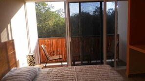 Relax in this serene bedroom with a large bed and sliding glass door leading to an outdoor area.