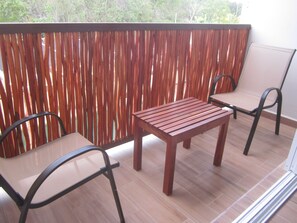 Relax on the balcony with a wooden table and two chairs, taking in the serene views of the surrounding trees.