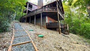 A cabin with a wooden deck and multiple levels, surrounded by trees and a gravel path. - Secluded Blue Ridge Cabin, Hot Tub/Mountain Views/Fire Pit/Family Game Rm (Blue Ridge)