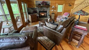 A cozy cabin interior with a stone fireplace, leather sofas, and a television. - Secluded Blue Ridge Cabin, Hot Tub/Mountain Views/Fire Pit/Family Game Rm (Blue Ridge)