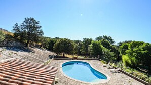 A swimming pool with a tiled deck, surrounded by trees and a stone wall. - Stunning home in Montaren et St Mediers (Montaren et St Mediers)