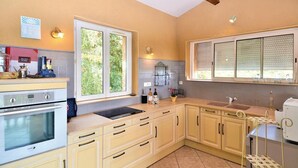 A kitchen with a stove, oven, sink, and window. There are cabinets, a countertop, and a hanging rack. - Stunning home in Montaren et St Mediers (Montaren et St Mediers)