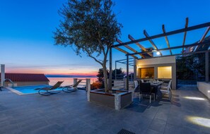 A rooftop pool area with lounge chairs, a pergola, and a dining table with chairs. - Lovely home in Jesenice (Jesenice)