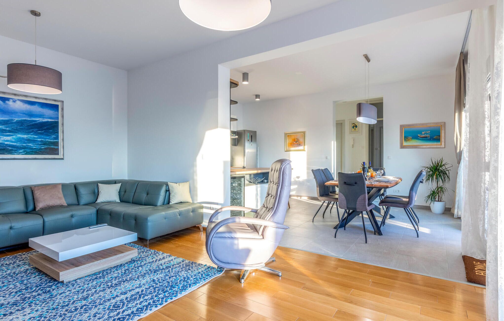 Ein modernes Wohnzimmer mit einem Ecksofa, einem Esstisch mit Stühlen und einer Küche im Hintergrund.