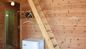 Un intérieur en bois avec un réfrigérateur blanc, une porte en bois et une échelle en bois.