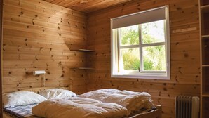 Une pièce de style cabane en bois, avec un lit, une fenêtre et un radiateur.