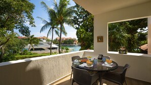 A balcony with a table set for breakfast, overlooking a marina with boats and palm trees. - Chac Hal Al, Casa Calandria lovely studio steps from the beach. (Puerto Aventuras)