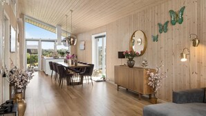 A spacious living area with a wooden ceiling, a dining area with a large table and chairs, and a cozy seating area with a sofa. - Gorgeous home in Væggerløse with WiFi (Væggerløse)