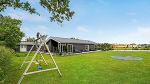 A modern house with a large backyard, including a swing set and a trampoline. - Gorgeous home in Væggerløse with WiFi (Væggerløse)