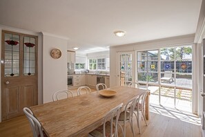 Enjoy meals in this dining area with a garden view, featuring a table and chairs, and a modern kitchen with oven.