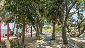 A wooden pathway leading to a beach area with benches and red structures. - Soundfront with Gorgeous View and Private Pier! (Kill Devil Hills)