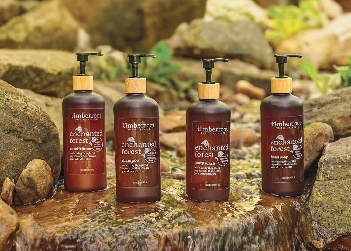 Four bottles of Enchanted Forest products on a wooden surface.
