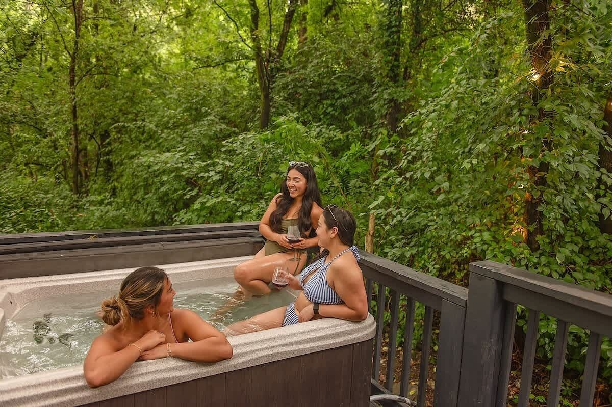 Een hottub in een bebost gebied met een houten terras.