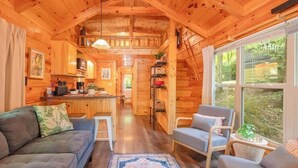 Un acogedor interior de cabaña con sofá, sillón y comedor.