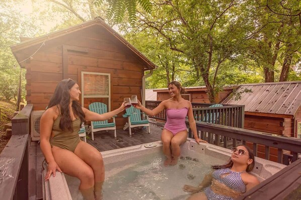 Una cabaña de madera con jacuzzi, rodeada de árboles.