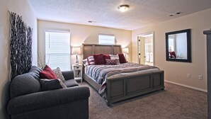 A bedroom with a large bed, a gray sofa, and a decorative wall piece. - Near Airport, University, Stadiums & more. Sleeps 8 by a Premier Partner Host! (Albuquerque)