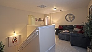 A living room with a staircase, a couch, and a decorative wall piece. - Near Airport, University, Stadiums & more. Sleeps 8 by a Premier Partner Host! (Albuquerque)