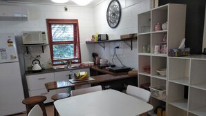 A compact kitchen with white cabinets, a microwave, a kettle, and a window with blinds. - Self Contained Studio - Air-conditioned WiFi (Parramatta Park)